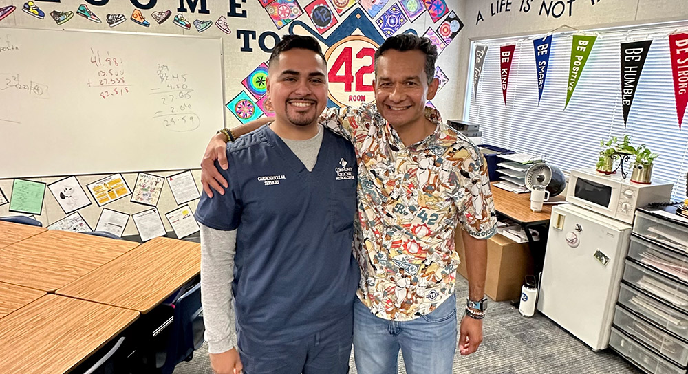 Anthony Hernandez and Robert Garcia stand arm in arm in the middle of Garcia's sixth grade classroom.