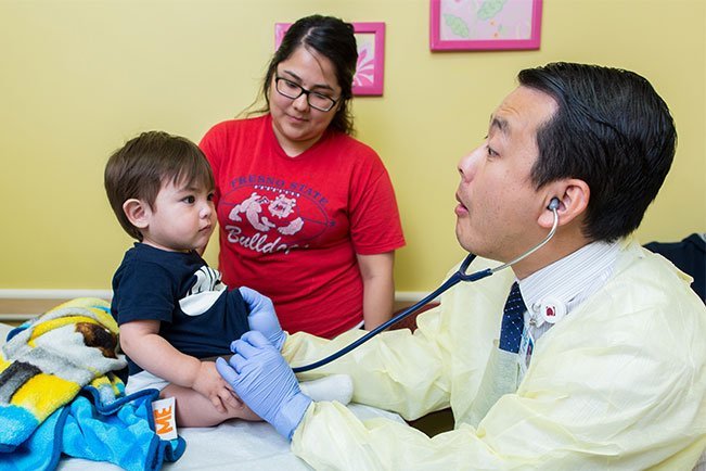 Eighteen-month-old Liam Espinosa eyes Pediatric Pulmonologist John Moua while his mother Natalie Espinosa watches.
